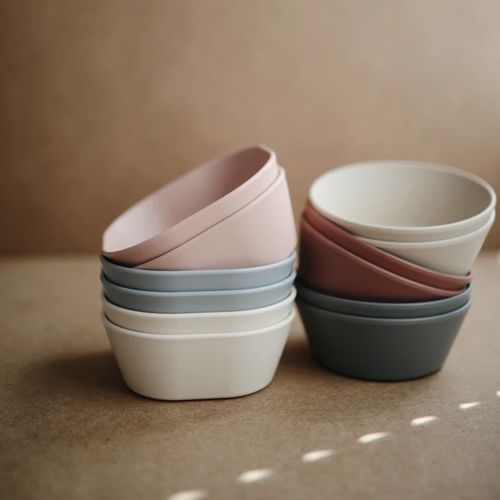 Twee stapels mushie kinderkommen in verschillende pastelkleuren.