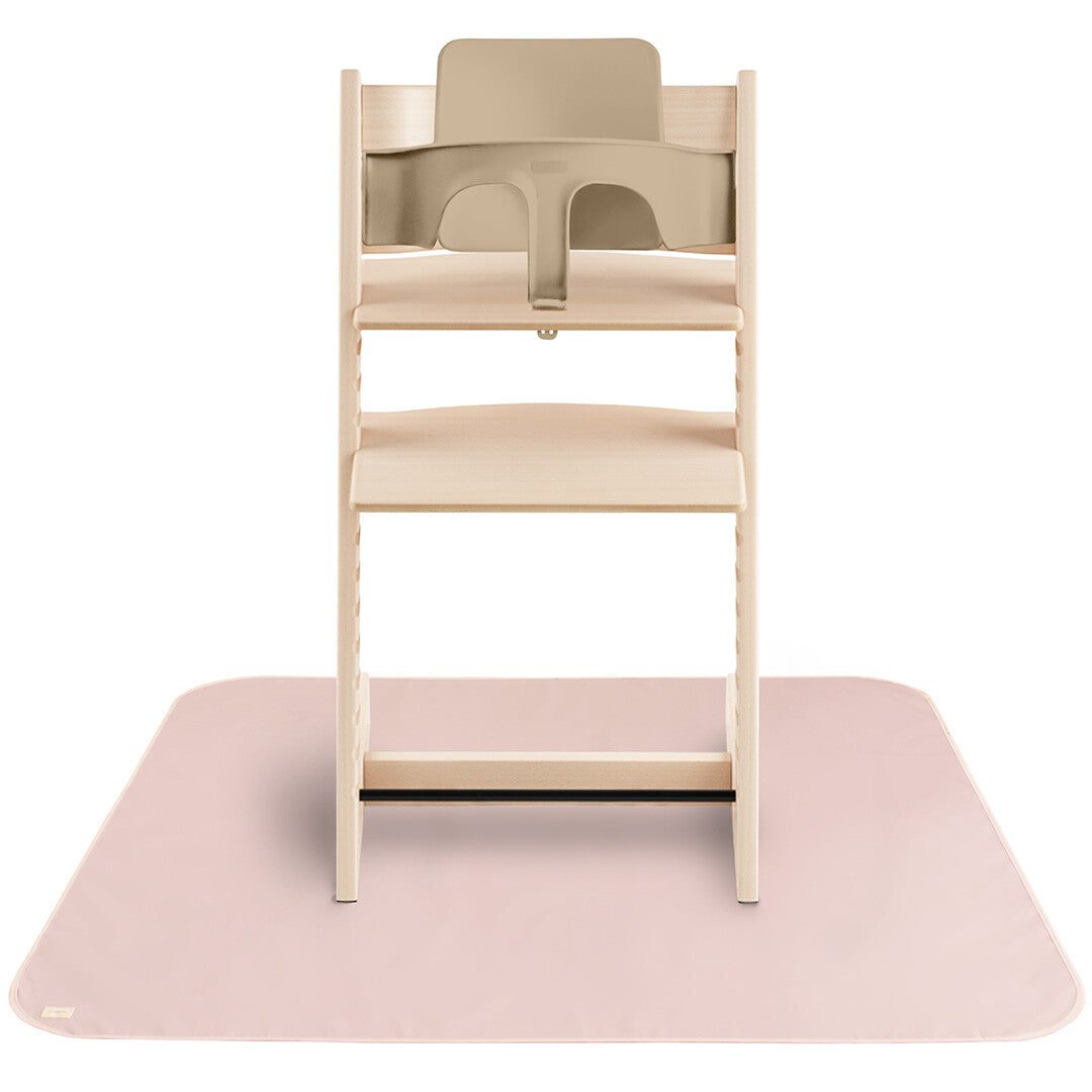 Mushie knoeimat in lichtroze kleur onder een houten kinderstoel.