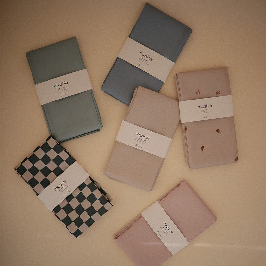 Een collectie van zes opgevouwen mushie knoeimatten in diverse kleuren en patronen.