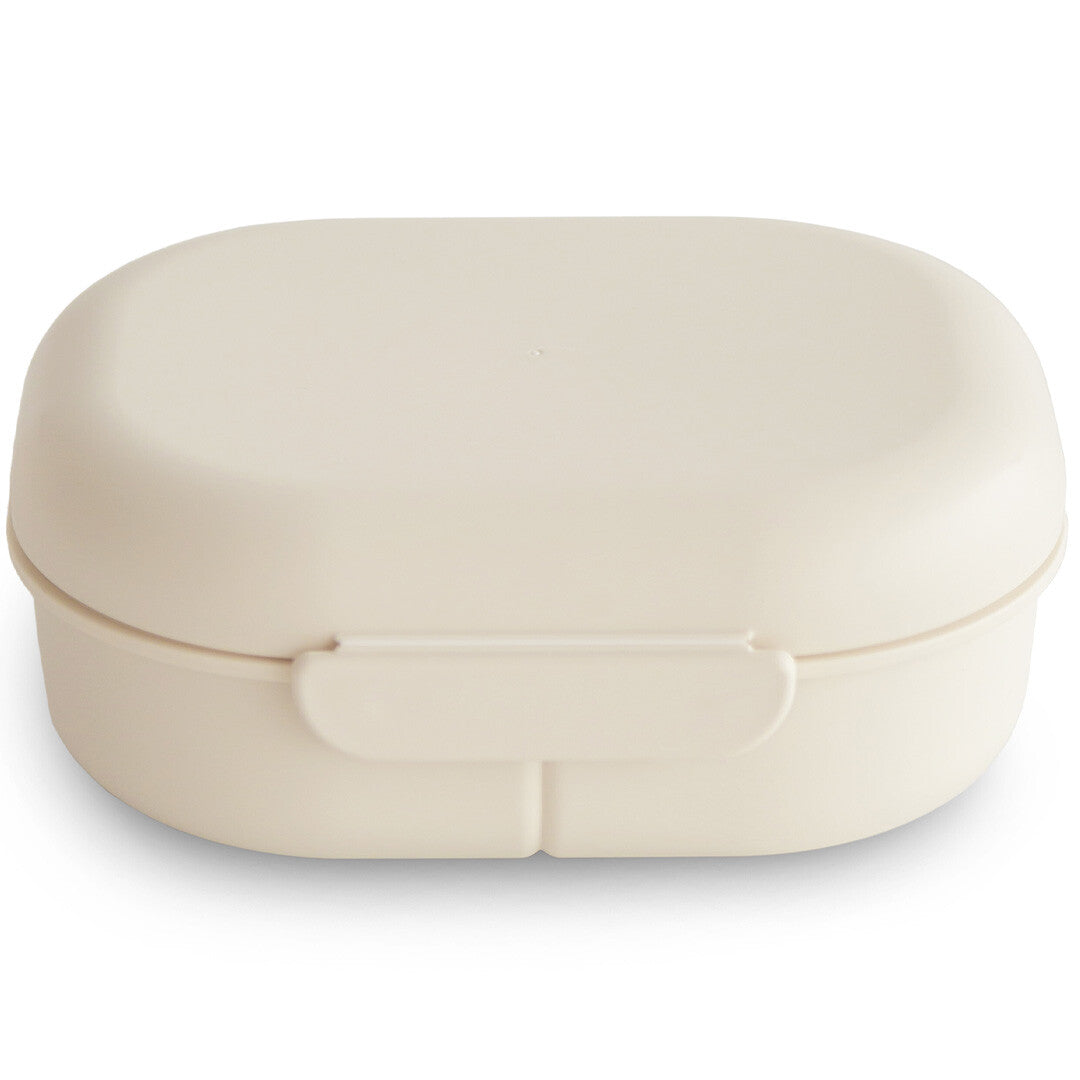 Gesloten mushie lunchbox in ivoor op een witte achtergrond.