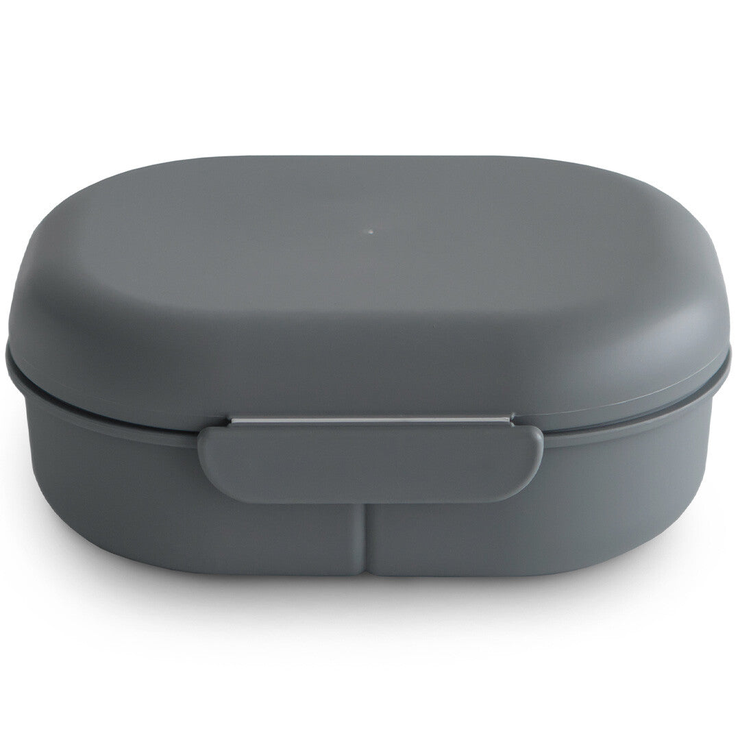 Mushie grijze lunchbox met bestek, gesloten en van opzij gefotografeerd.