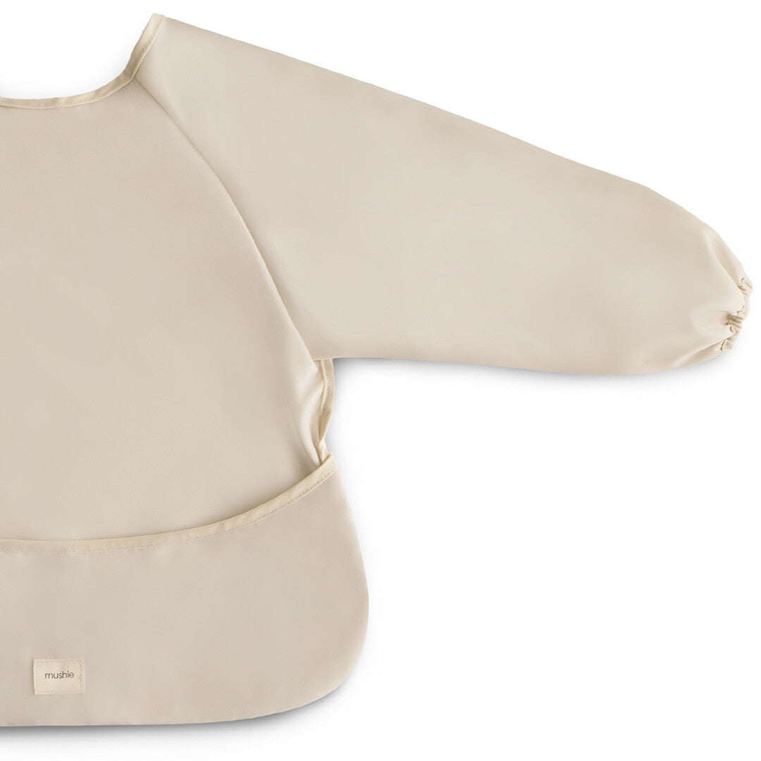 Detailopname van de mushie beige mouwslab met lange mouw en opvangzakje.