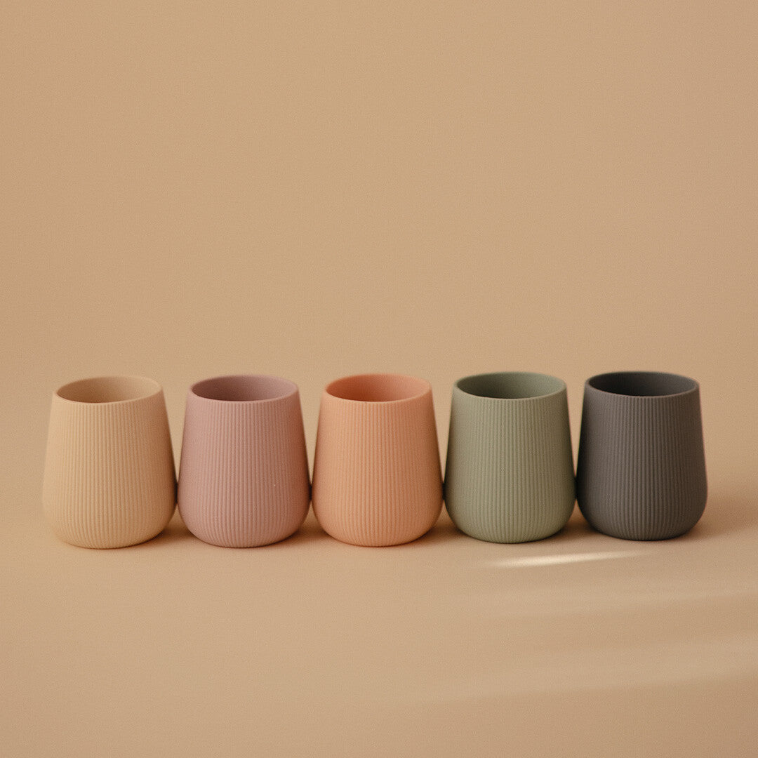 Collectie van vijf mushie peuterbekers in verschillende pastelkleuren met verticale ribbels.