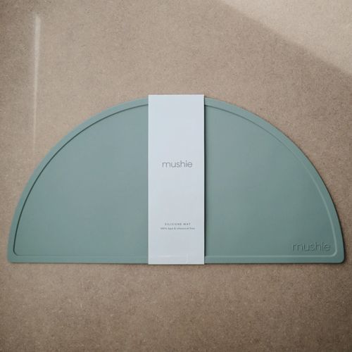 Mushie placemat in Cambridge blue met de witte verpakkingsband eromheen.