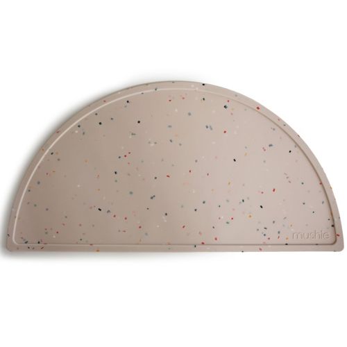 Mushie beige placemat in een halve cirkel vorm met kleurrijke confetti stippen.