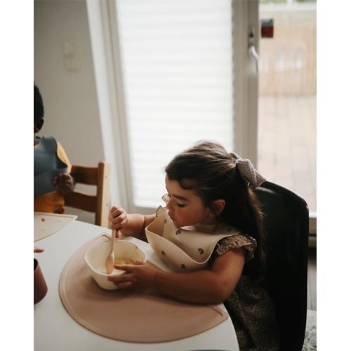 Een kind eet van een kom op een roze baby placemat.