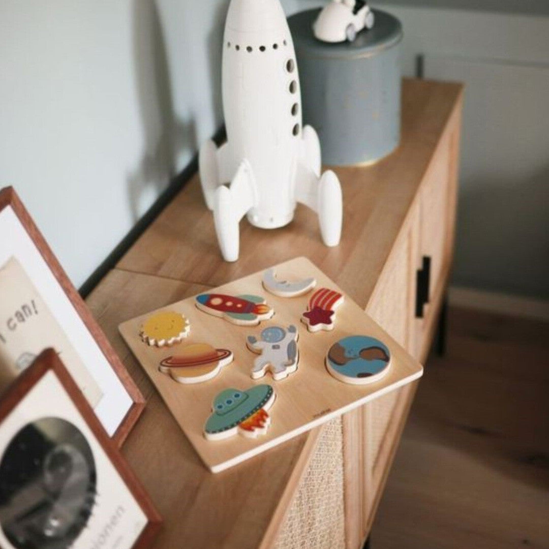 mushie houten puzzel met ruimtefiguren op een houten kastje.