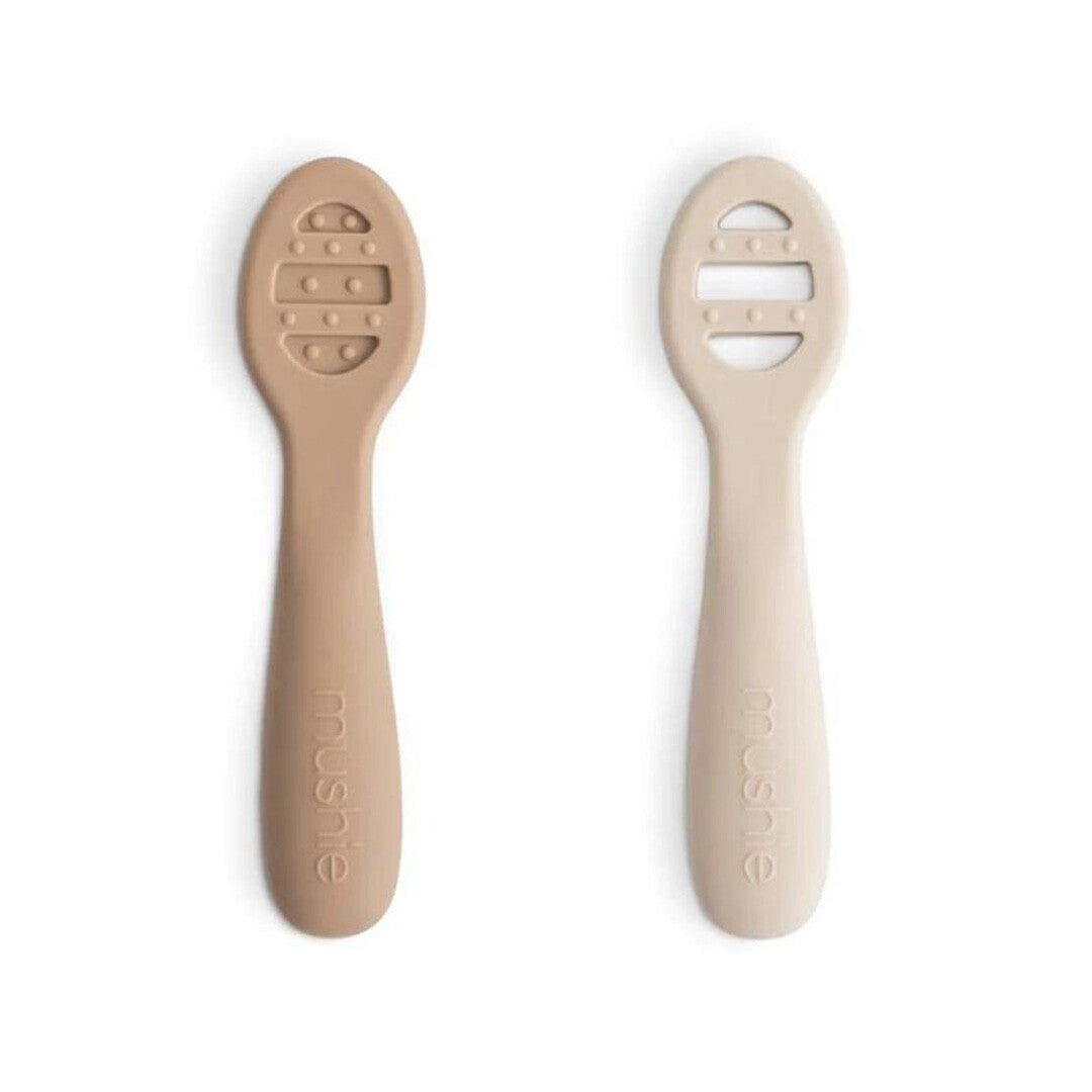 Twee Mushie sensorische babylepels in beige en lichtbeige met gestructureerde koppen.