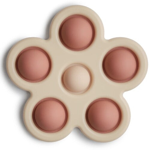 Mushie sensorische bloem babyspeelgoed met roze en zandkleurige bubbels.