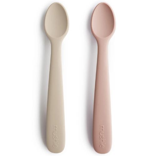 Twee Mushie siliconen babylepels in beige en roze liggen naast elkaar.
