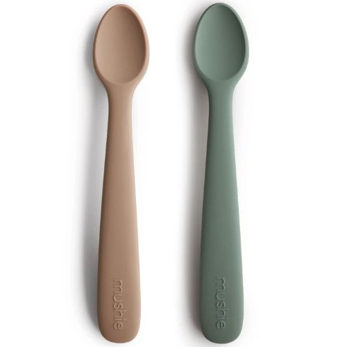 Twee Mushie siliconen babylepels in beige en groen.