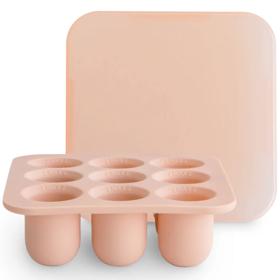 Mushie roze siliconen invriesvorm voor babyvoeding met negen vakjes en een deksel.