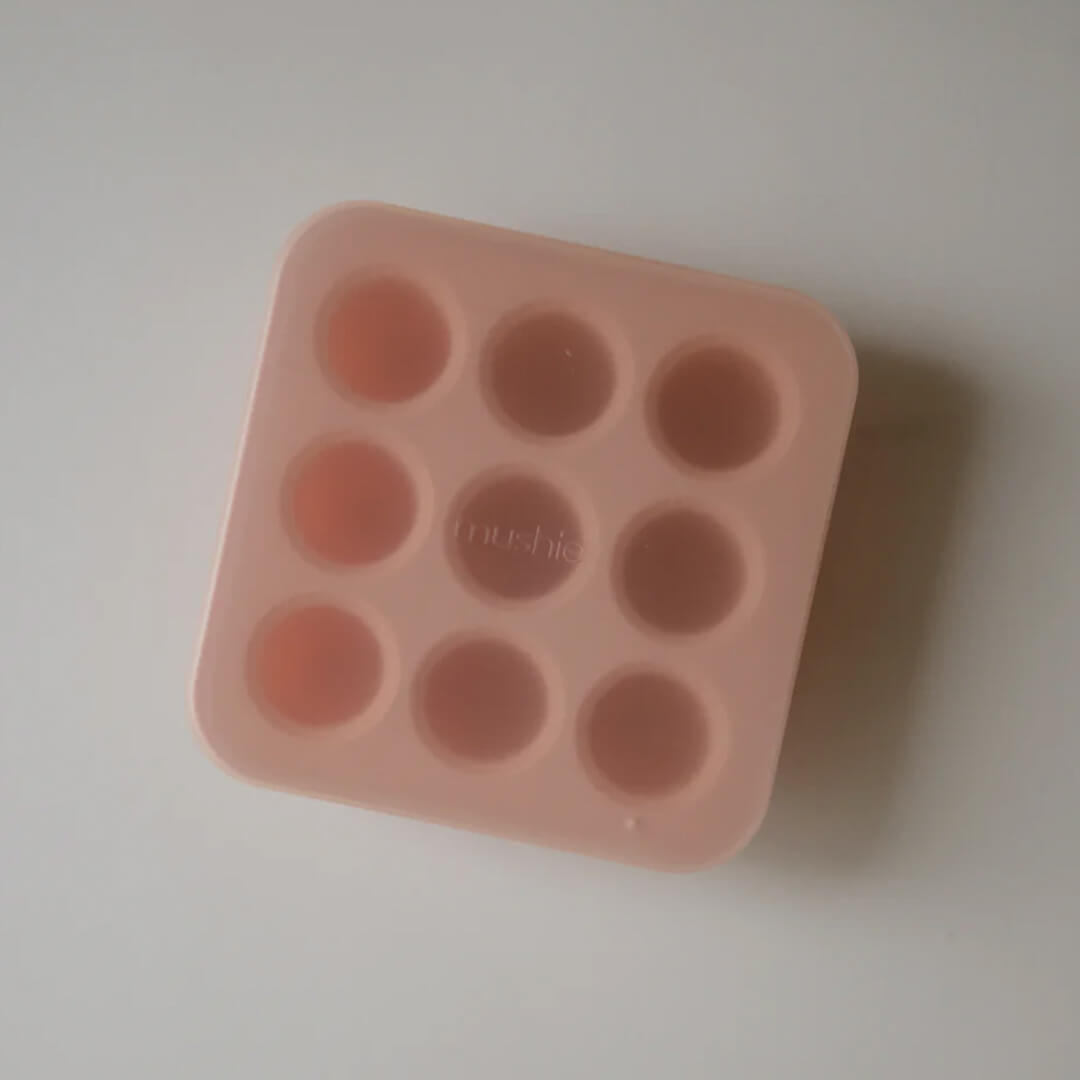 Mushie roze siliconen invriesvorm voor babyvoeding met negen ronde vakjes, van bovenaf gezien.