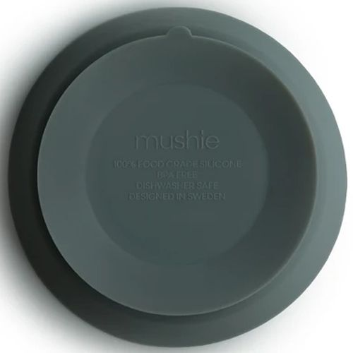 De onderkant van de mushie siliconen kinderkom in dried thyme, met merknaam en productinformatie.