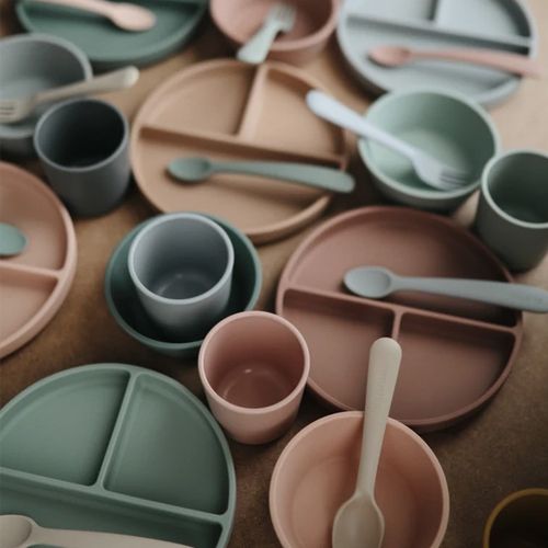 Een collectie mushie siliconen babyvoedingsartikelen in verschillende pastelkleuren.