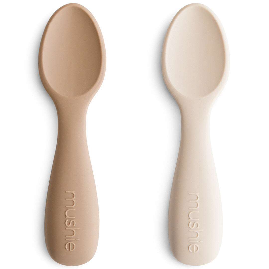 Twee Mushie siliconen voederlepels in beige en lichtbeige op een witte achtergrond.