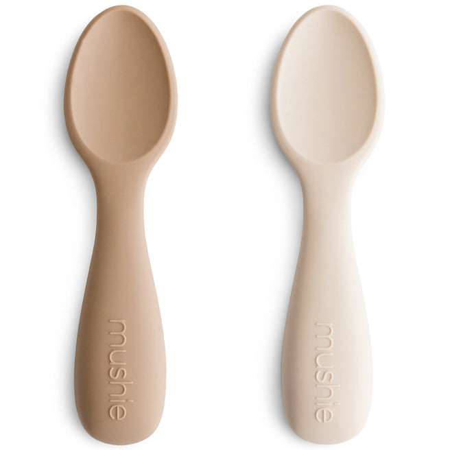 Twee Mushie siliconen voederlepels in beige en lichtbeige op een witte achtergrond.