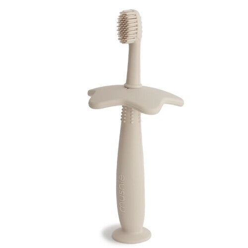 Mushie siliconen kindertandenborstel in beige met stervormige bescherming.