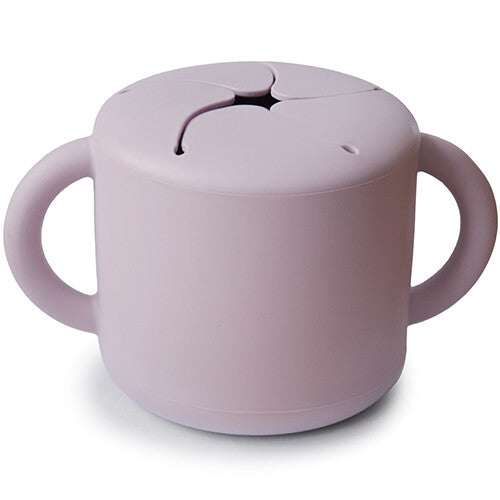 Mushie siliconen snackbeker in zacht lila met twee handvatten en een flexibele deksel.