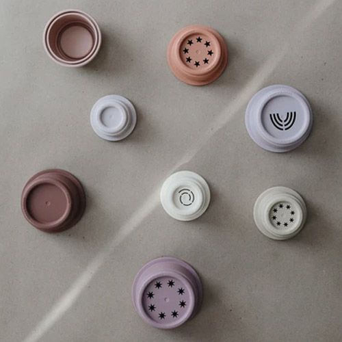 Losse Mushie stapelbekers voor peuters, met verschillende patronen zoals sterren en een wervel op de bodem.