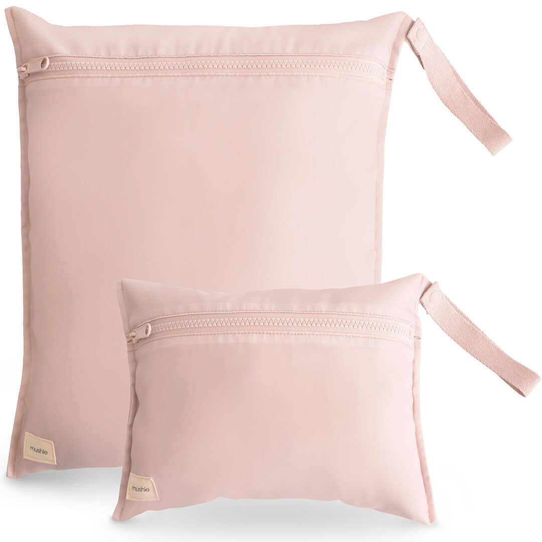 Twee roze Mushie waterproof opbergzakken van polyester, een grote en een kleine, met ritsen en lussen.