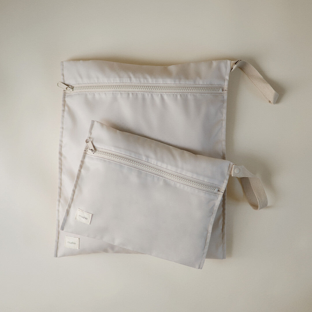 Twee mushie waterdichte opbergzakken in beige, een grote en een kleine, plat op een lichte ondergrond.