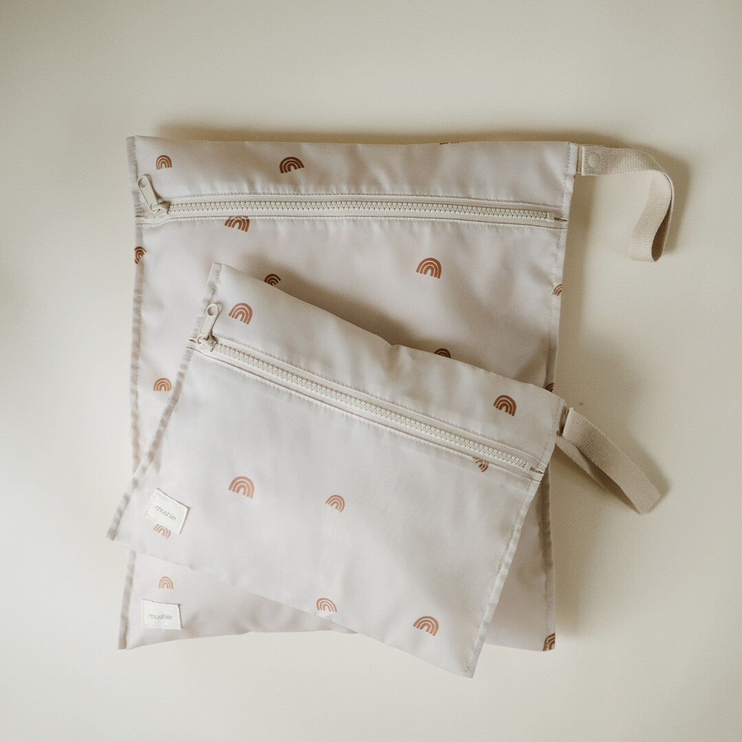 Twee mushie waterproof opbergzakken in beige met regenboogpatroon, van bovenaf gefotografeerd.