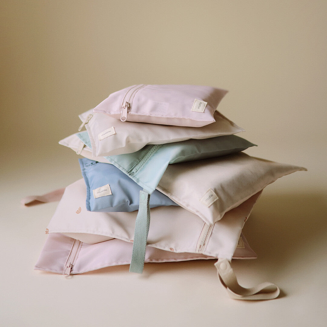 Een stapel mushie waterproof opbergzakken in verschillende pastelkleuren.