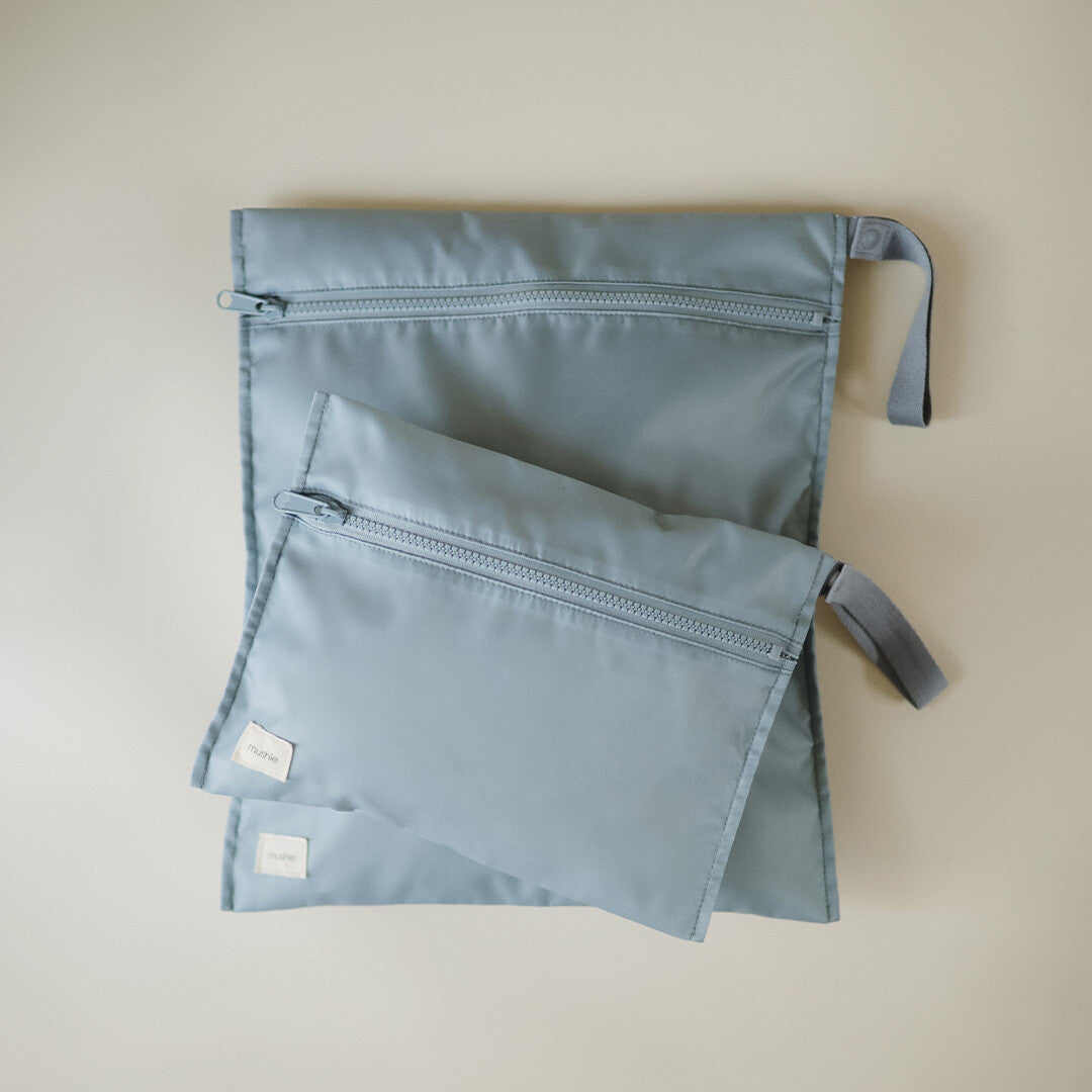 Twee platte, lichtblauwe mushie waterproof opbergzakken, een grote en een kleine, op een lichte ondergrond.