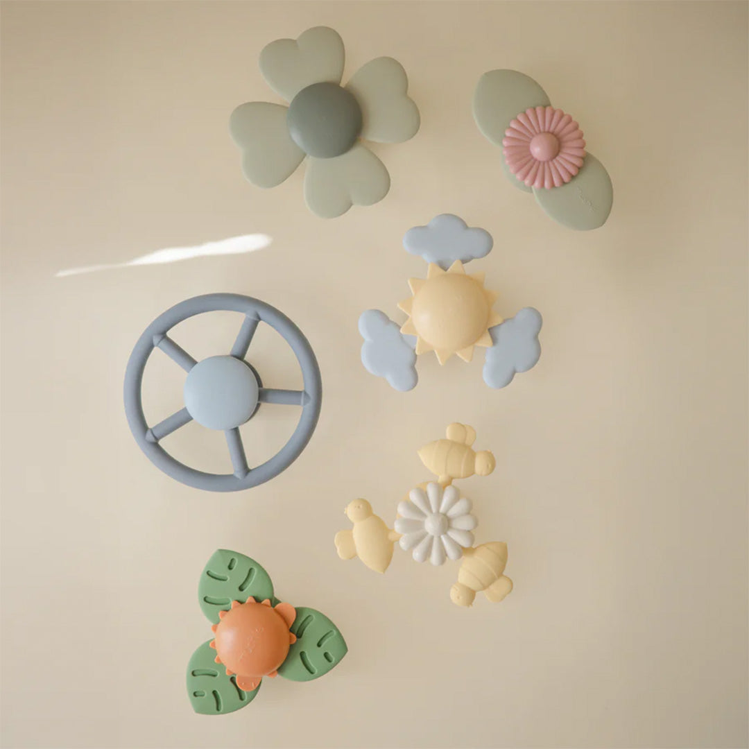 Een collectie mushie babyspeelgoed spinners met zuignap in verschillende vormen, waaronder een stuur, bloemen, zon en bijen.