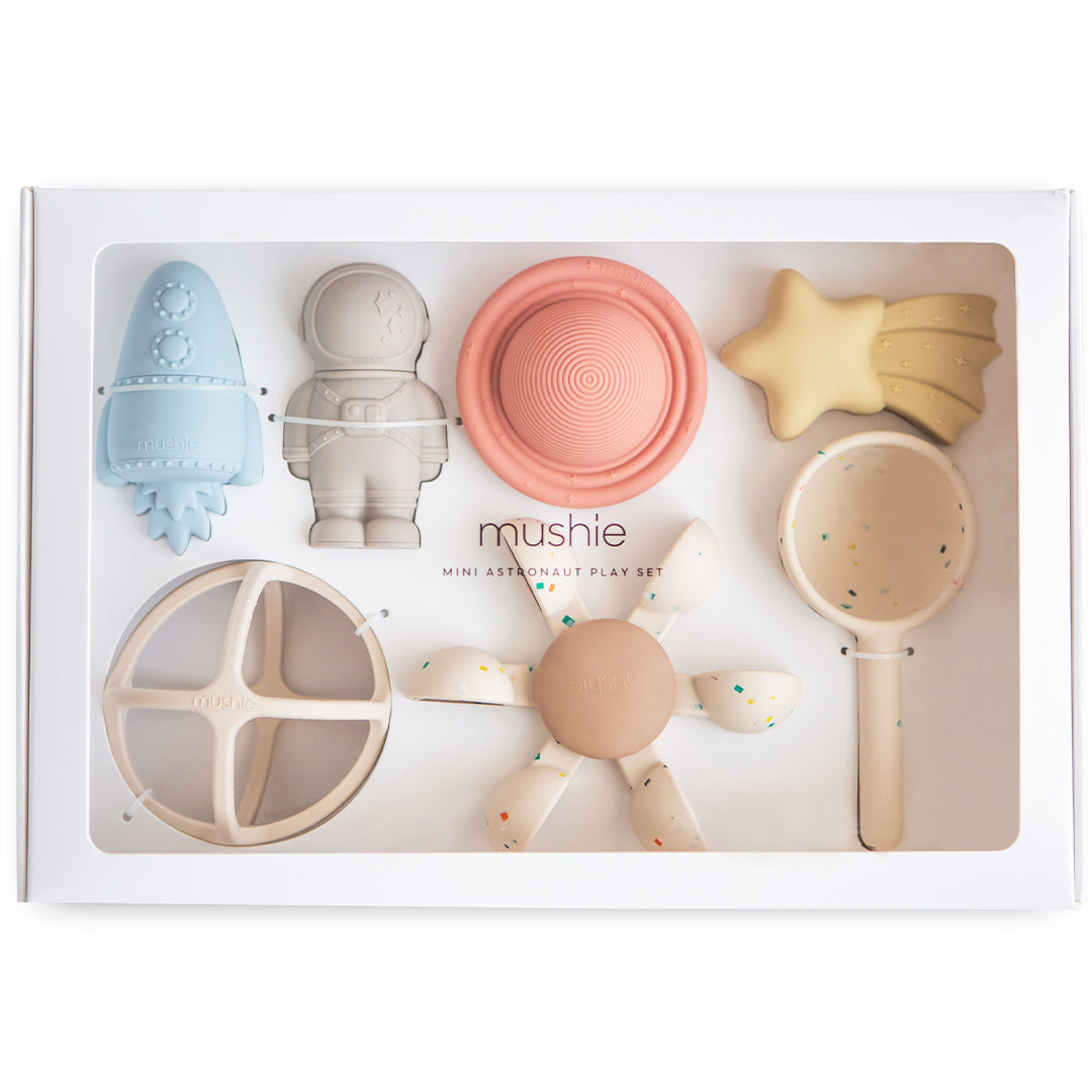 Mushie geschenkdoos met zeven siliconen babyspeeltjes in astronautenthema, waaronder een raket, astronaut en ster.