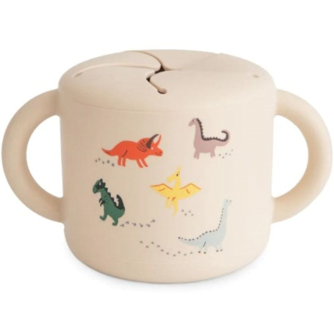 Mushie siliconen snackbeker voor baby's en peuters, beige met kleurrijke dinosauruspatronen.