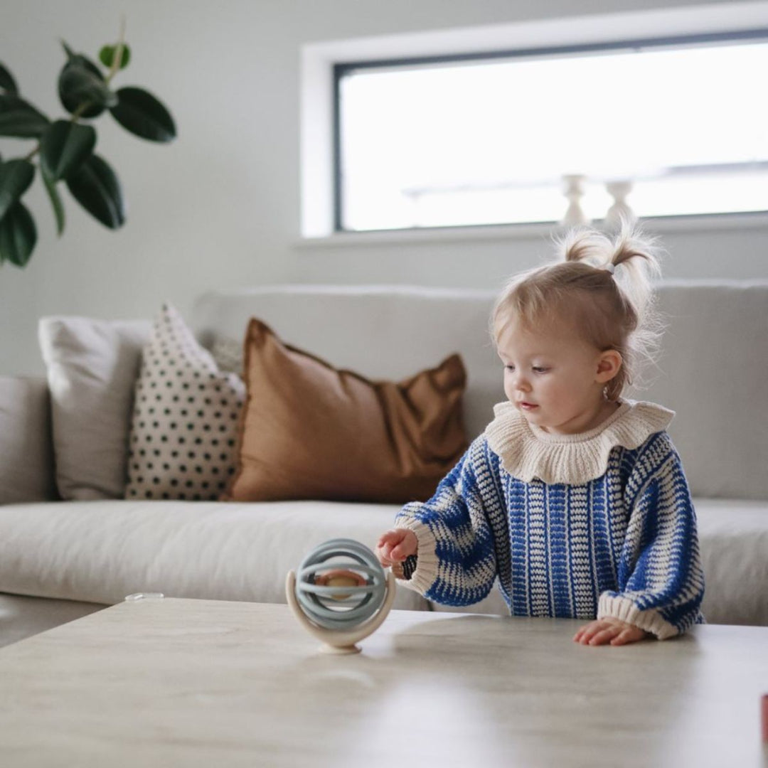 Een baby speelt met de mushie spinner bal met zuignap op een tafel.