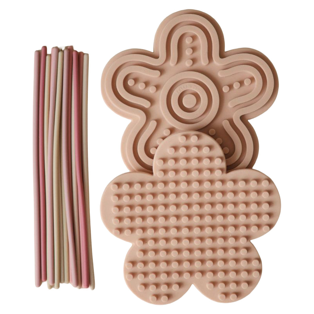 mushie sensorisch babyspeelgoed bestaande uit twee roze bloemvormige speeltjes met verschillende texturen en een bundel gekleurde stokjes.