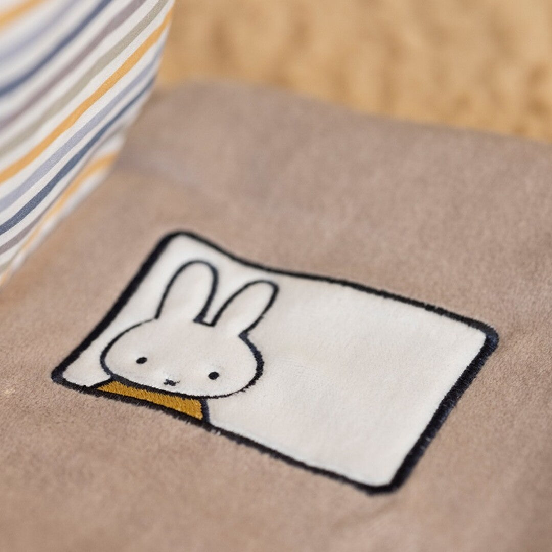 Detail van een beige pagina van het Nijntje-miffy activiteitenboek met een geborduurde Nijntje.