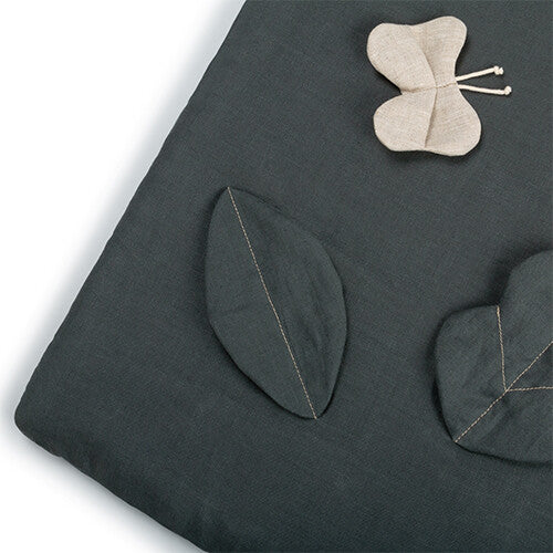 Detail van het donkergroene speelkleed met een stoffen blad en een stoffen vlinder.