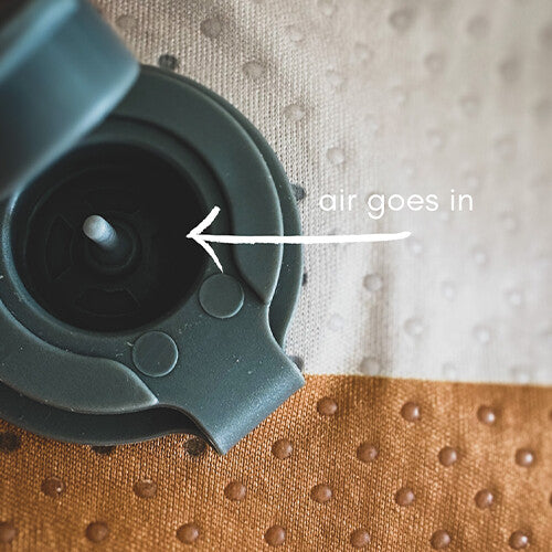 Detail van het ventiel van het opblaasbare stoelkussen met de tekst 'air goes in'.