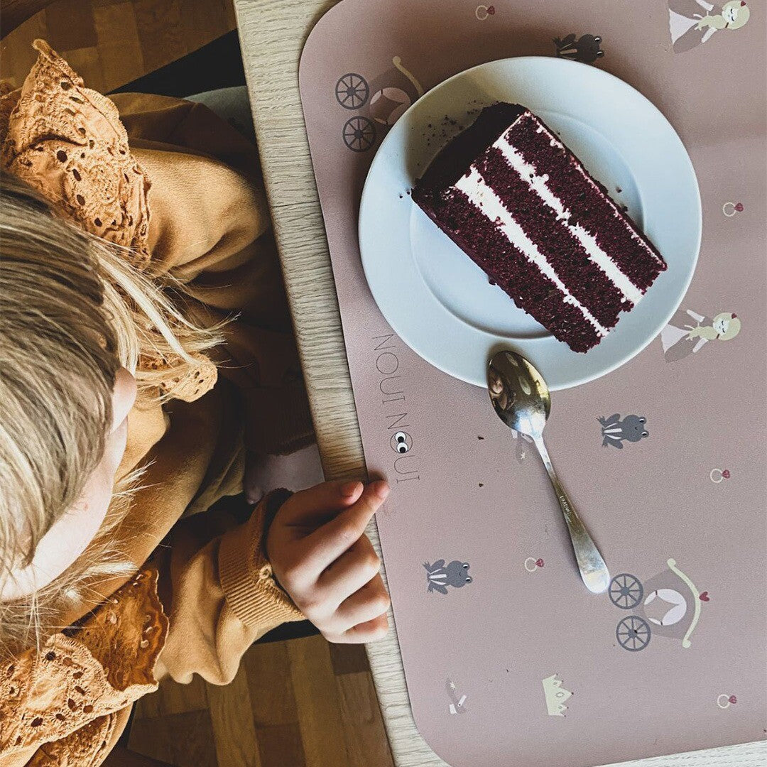Een kind eet taart van een bord op de Noui Noui placemat met prinsessenpatroon.