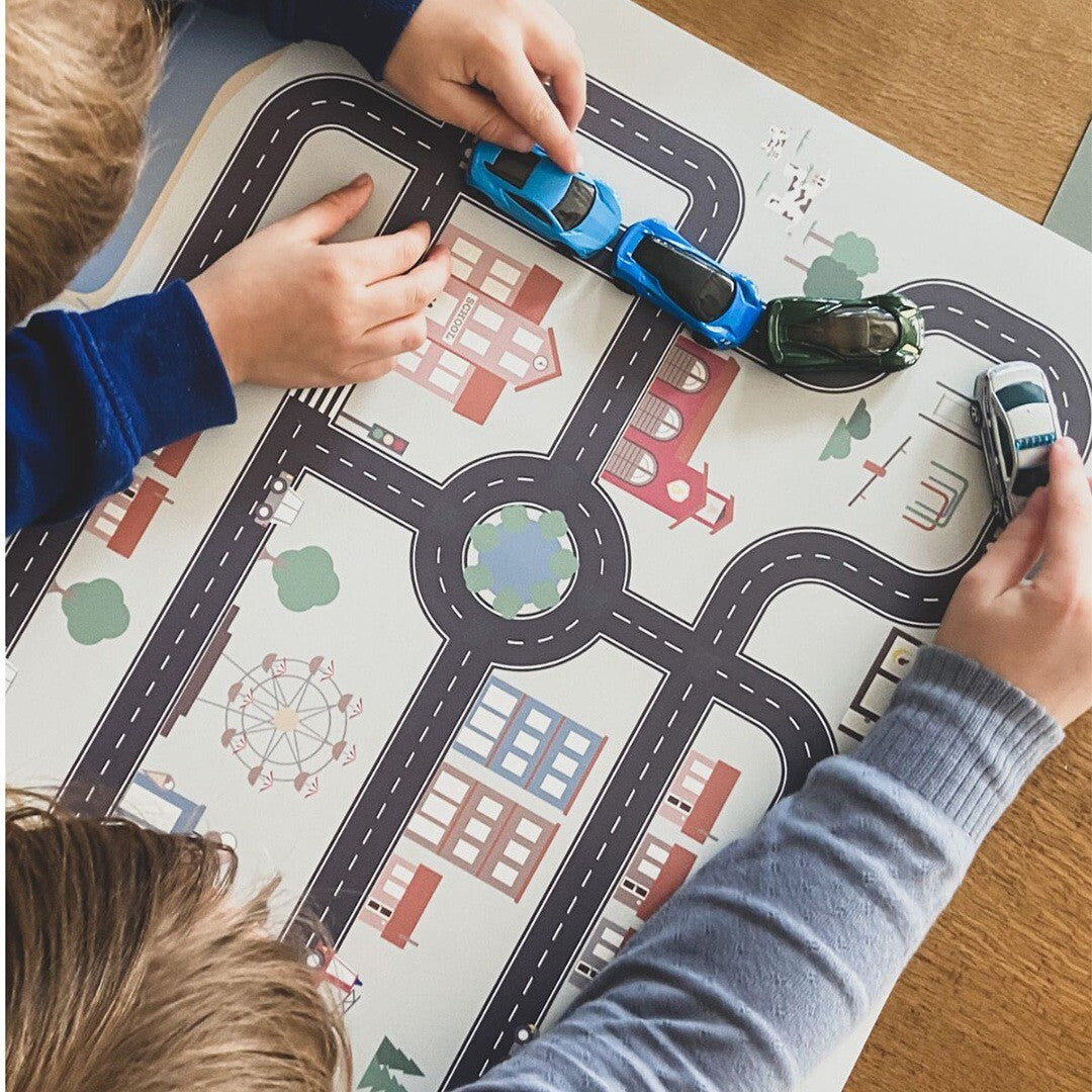 Twee kinderen spelen met speelgoedauto's op de Noui Noui placemat met wegenpatroon.