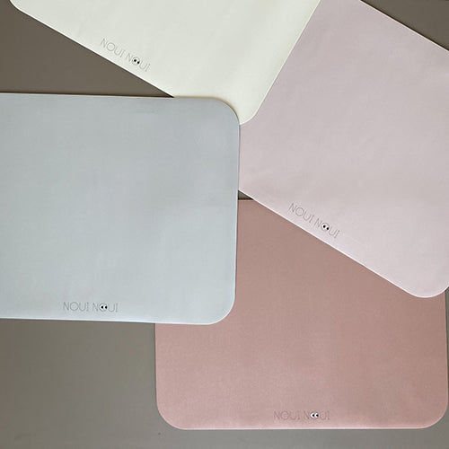 Vier noui noui placemats in verschillende pastelkleuren, waaronder oudroze, grijs en crème.
