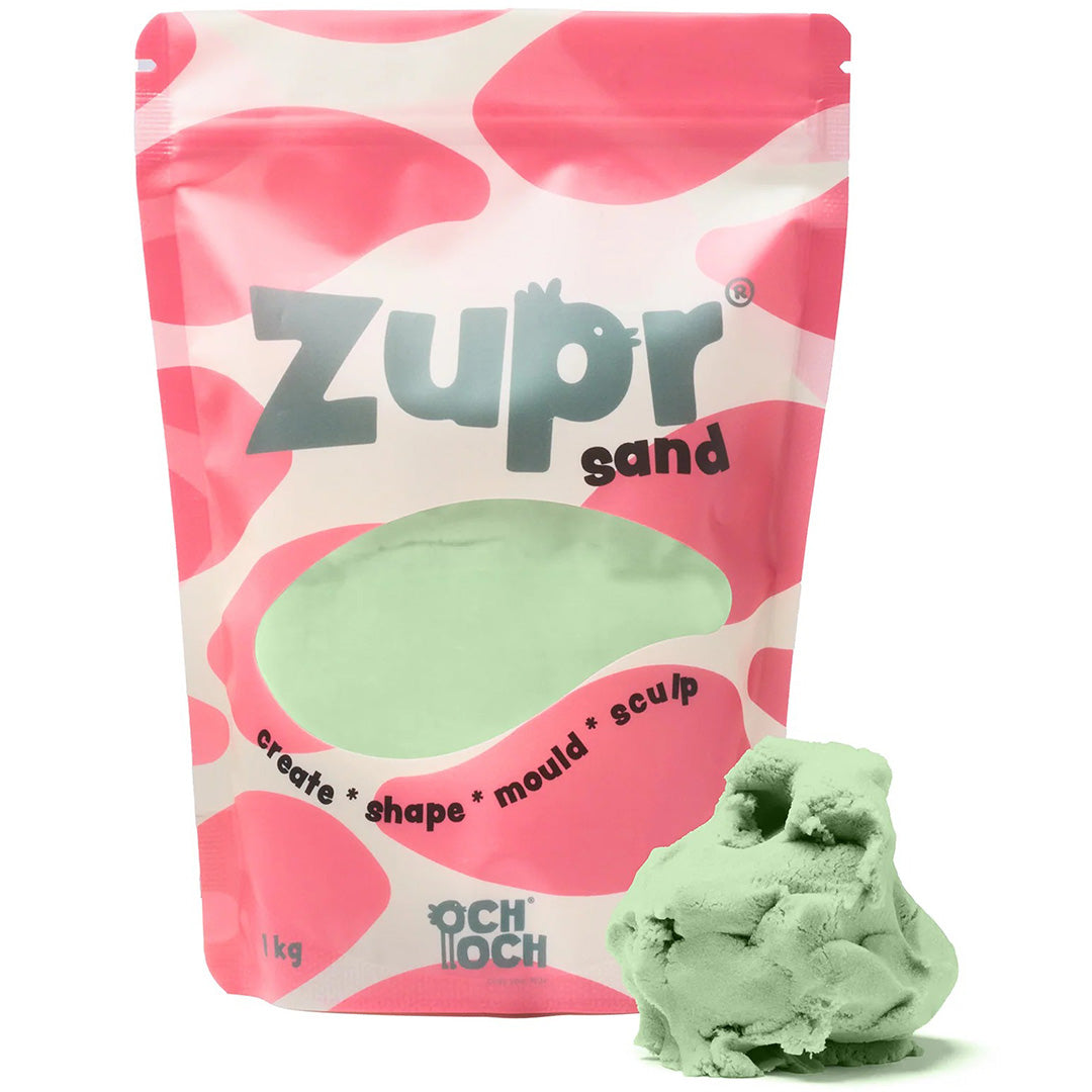 Och Och Zupr kinetisch zand in een roze-witte verpakking met een hoopje groen zand ernaast.