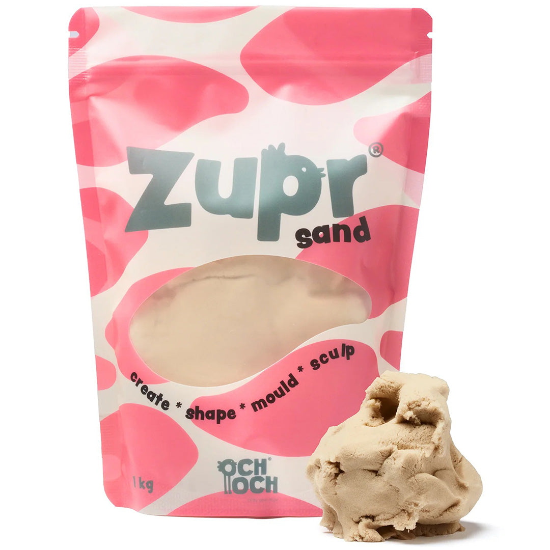 Och Och Zupr kinetisch zand in een roze-witte verpakking met een hoopje beige zand ernaast.
