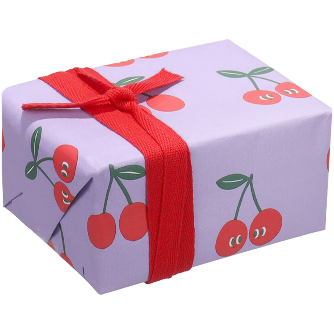 Een ingepakt cadeau met ole inpakpapier met kersenpatroon en een rood lint.