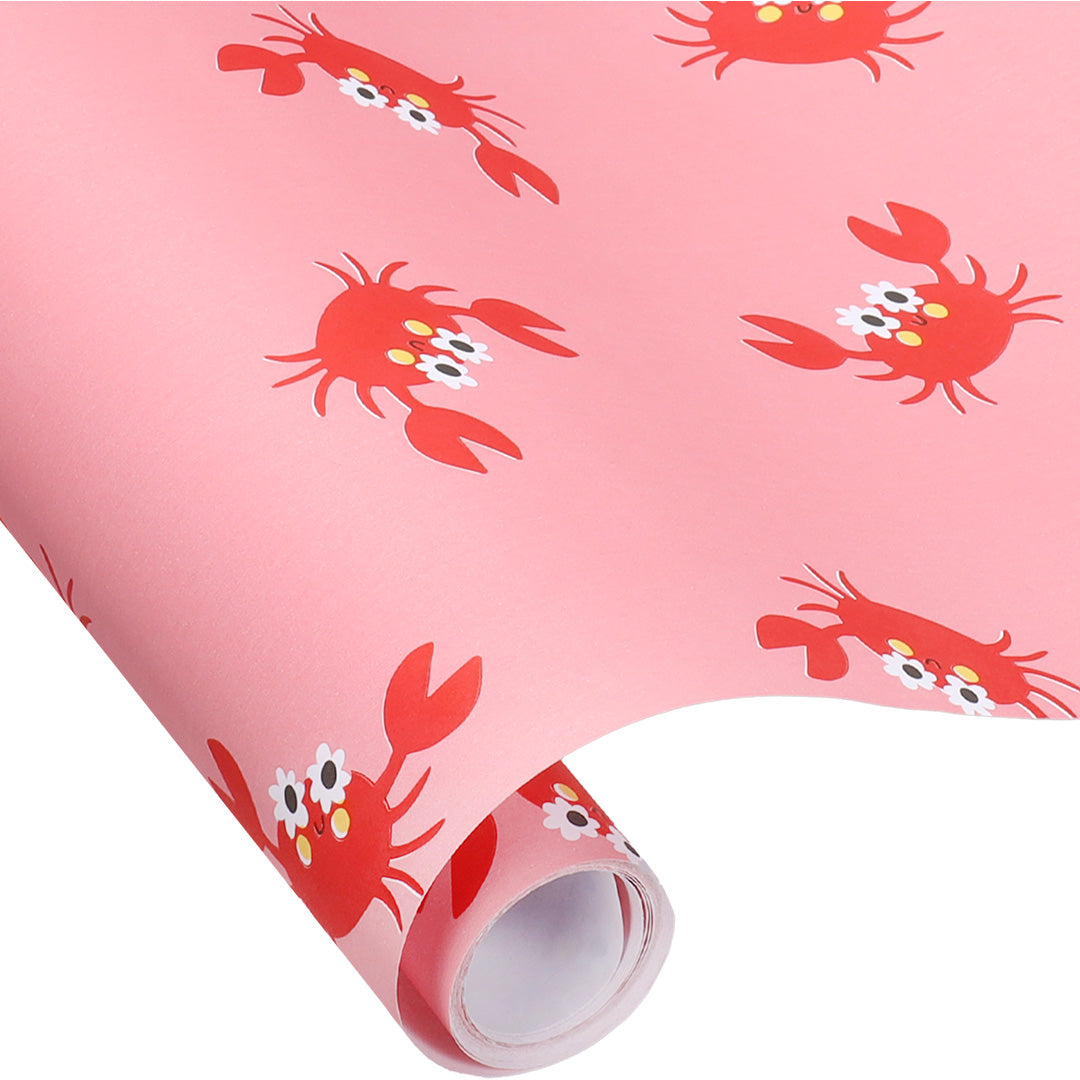 Een rol Ole inpakpapier met een patroon van rode krabben op een roze achtergrond, deels afgerold.