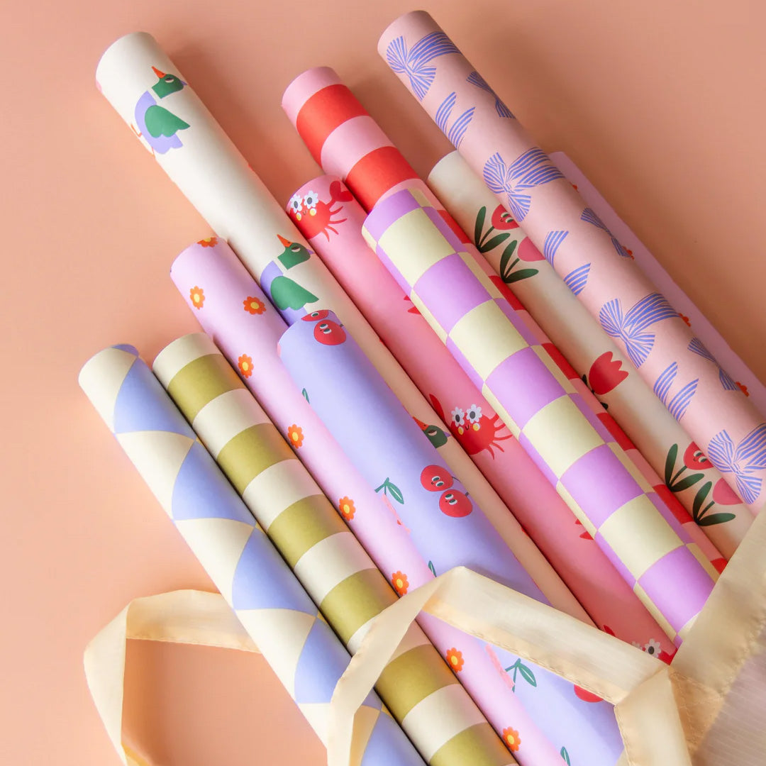 Een collectie van verschillende rollen ole inpakpapier met diverse patronen, waaronder gestreept en bloemen, in een tas.
