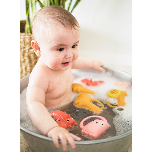 Een baby zit in een badje met verschillende Oli & Carol dieren bad- en bijtspeeltjes.