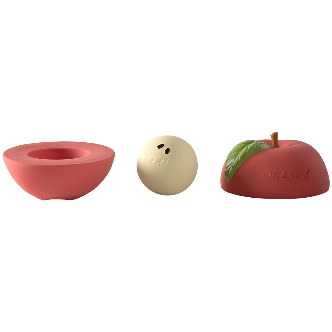De drie losse onderdelen van de Oli & Carol 3-in-1 babyspeelbal: twee rode appelhelften en een crèmekleurige rammelaar.