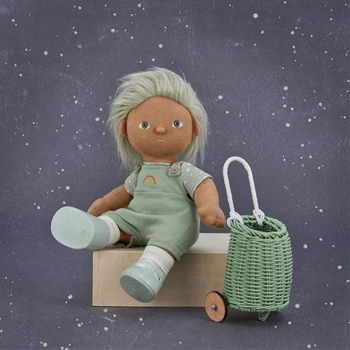 Een olli ella Dinkum Doll zit naast een mintgroene poppenluggy op een houten blok.