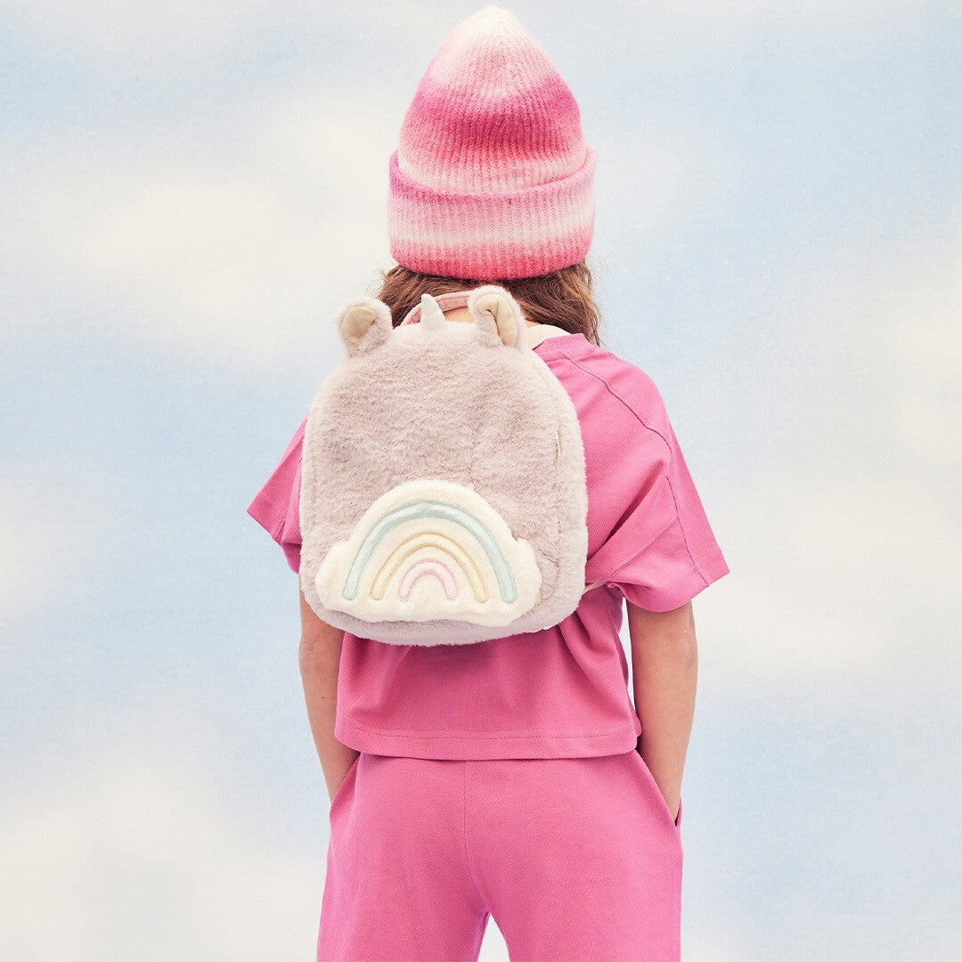 Kind van achteren gezien met de Olli Ella lila eenhoorn kleuterrugzak met regenboog op de rug.