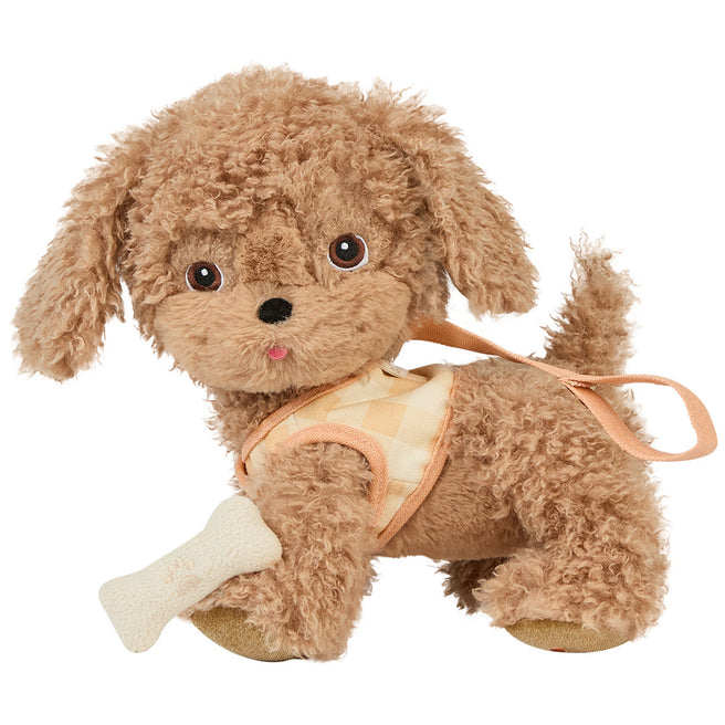 Olli Ella knuffelhond Goldie, een bruine pluchen hond met geruit tuigje en een botje in de bek, staat schuin.